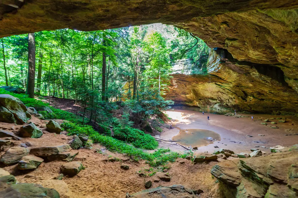 Visitors stand beneath the broad overhang at Ash Cave.